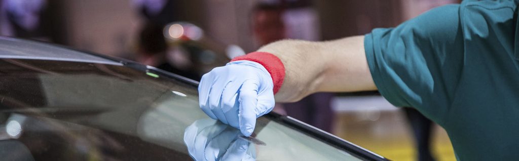 A person wearing gloves and rubber glove is working on a glass.