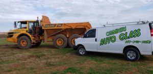 A white truck and yellow dump truck in the grass.