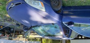 A blue car with some broken windows on the hood